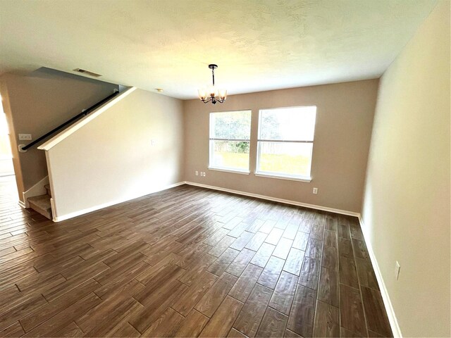 unfurnished room featuring an inviting chandelier and dark wood-type flooring