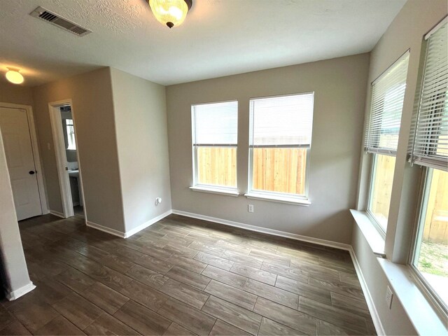 spare room with a textured ceiling and dark hardwood / wood-style floors