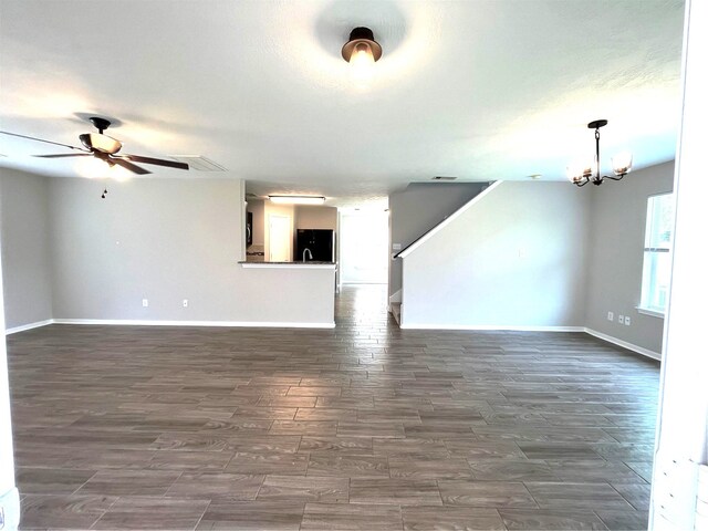 unfurnished living room with ceiling fan with notable chandelier and dark hardwood / wood-style floors