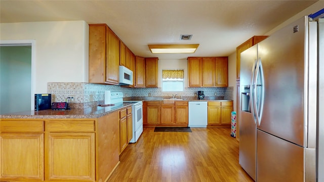 kitchen with backsplash, white appliances, kitchen peninsula, light wood-type flooring, and sink