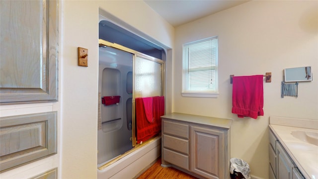 bathroom with wood-type flooring, enclosed tub / shower combo, and vanity