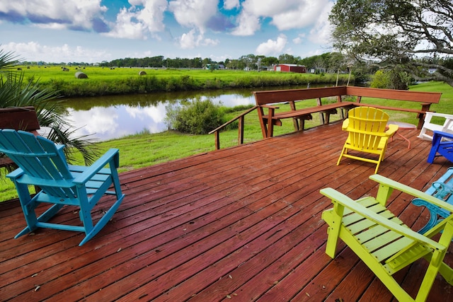 wooden deck featuring a lawn, a water view, and a rural view