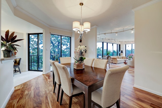 dining space featuring ornamental molding, light hardwood / wood-style floors, and an inviting chandelier