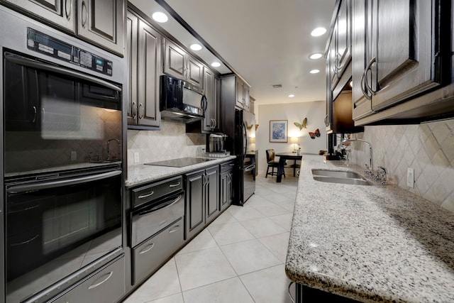 kitchen with decorative backsplash, black appliances, sink, and light stone counters