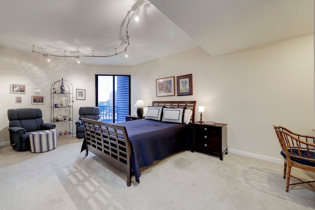 carpeted bedroom featuring rail lighting and a textured ceiling