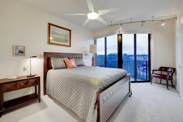 carpeted bedroom featuring access to outside, rail lighting, and ceiling fan