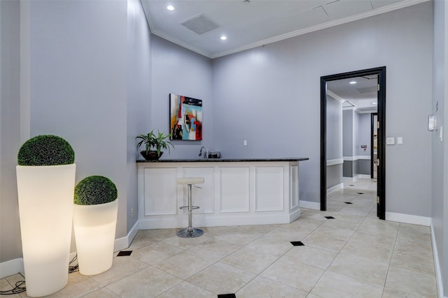 hallway with sink, light tile patterned floors, and crown molding