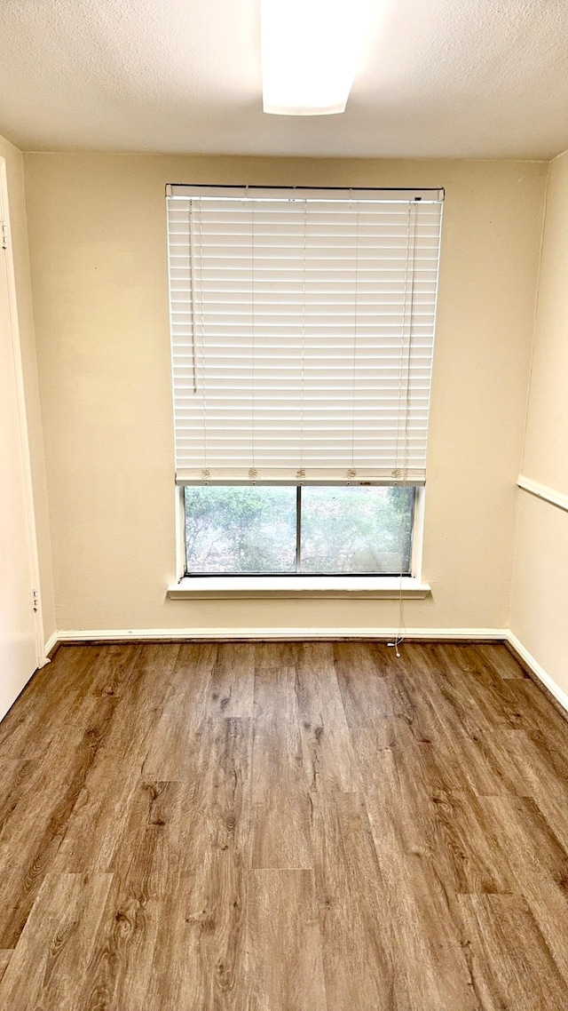 unfurnished room with hardwood / wood-style flooring and a textured ceiling