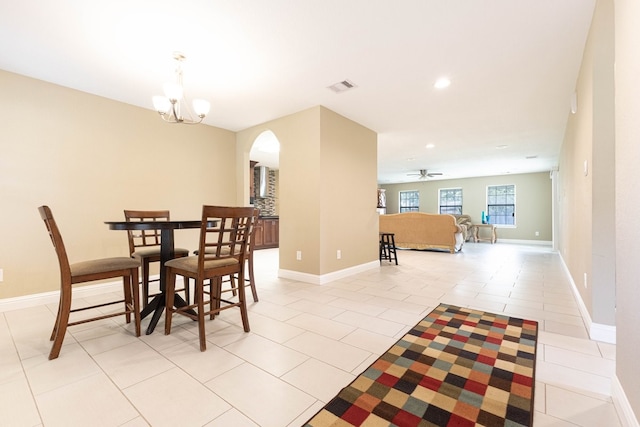 dining area featuring light tile patterned floors and ceiling fan with notable chandelier