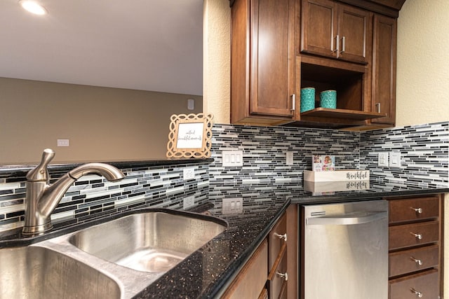 kitchen with stainless steel dishwasher, dark stone counters, and sink