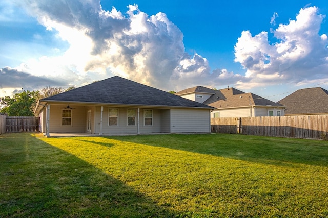 rear view of property featuring ceiling fan, a yard, and a patio