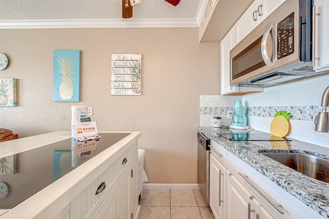 kitchen with white cabinetry, tasteful backsplash, light tile patterned floors, stainless steel appliances, and ornamental molding