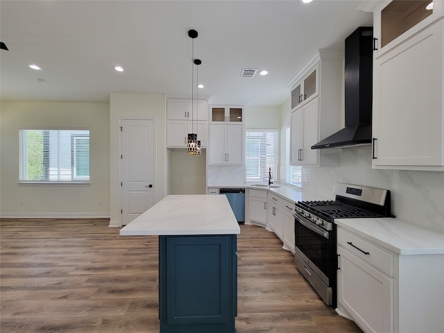 kitchen with a healthy amount of sunlight, stainless steel appliances, a kitchen island, and wall chimney range hood