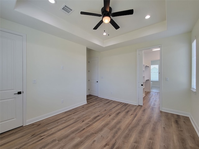 unfurnished bedroom featuring light hardwood / wood-style floors, a tray ceiling, and ceiling fan