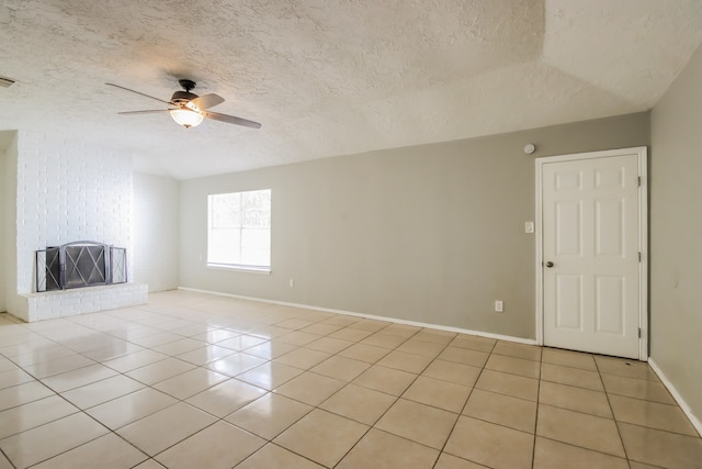 interior space with ceiling fan, a textured ceiling, a brick fireplace, and light tile patterned flooring