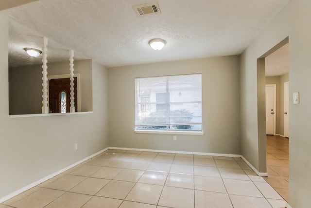 unfurnished room with a textured ceiling and light tile patterned floors