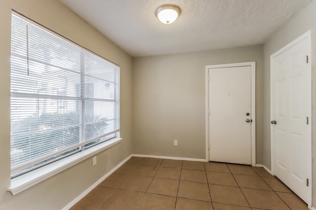 spare room with a textured ceiling and tile patterned floors