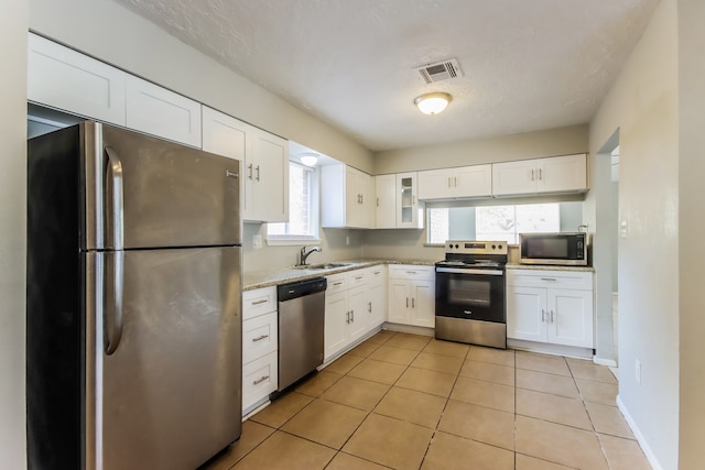 kitchen with a wealth of natural light, stainless steel appliances, sink, and white cabinetry