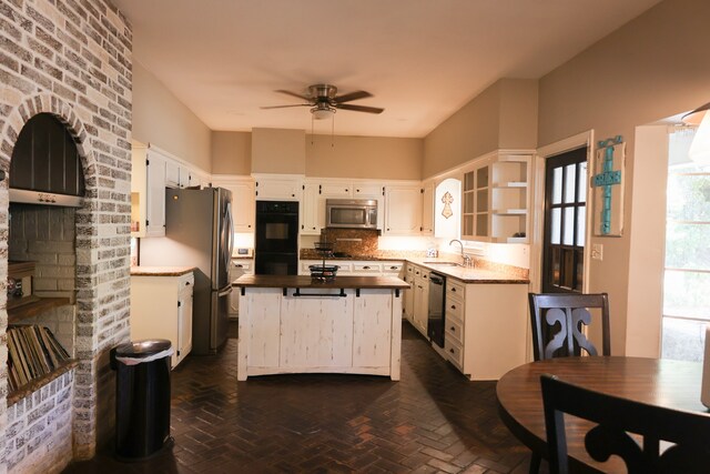 kitchen featuring white cabinetry, a kitchen island, stainless steel appliances, ceiling fan, and sink