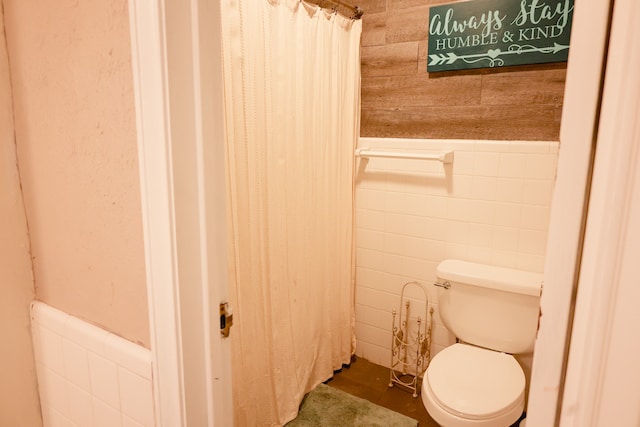 bathroom featuring tile walls, a shower with curtain, and toilet