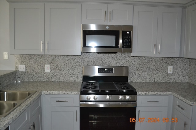 kitchen with white cabinets, stainless steel appliances, sink, and decorative backsplash