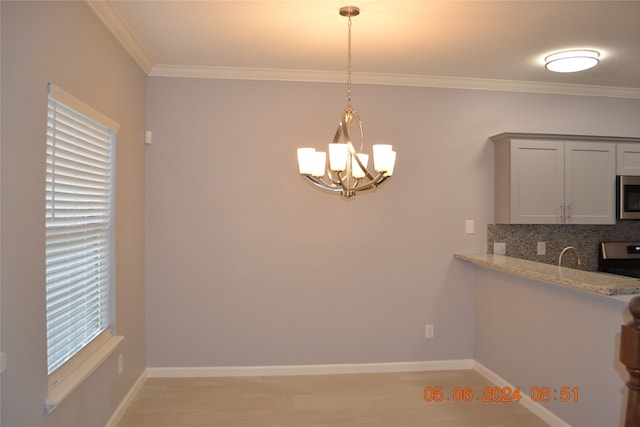 unfurnished dining area with a healthy amount of sunlight, crown molding, and a notable chandelier