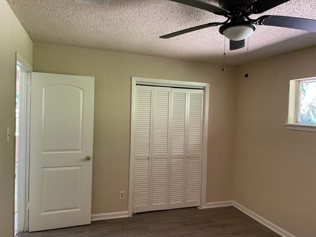 unfurnished bedroom with ceiling fan, dark hardwood / wood-style floors, a textured ceiling, and a closet