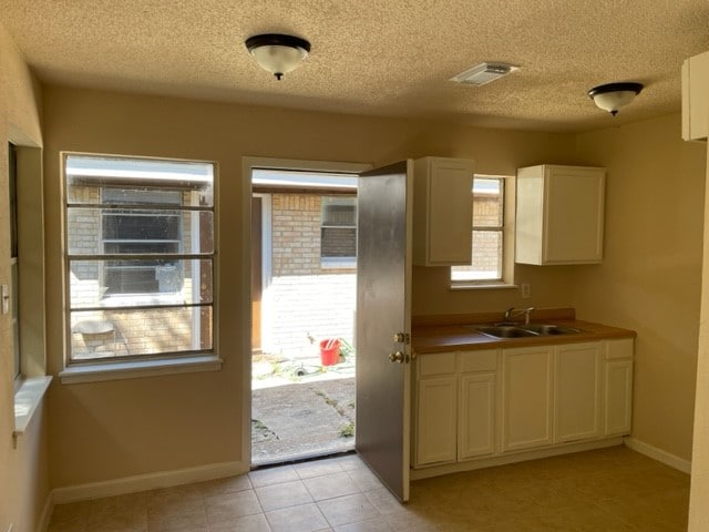 doorway featuring light tile patterned flooring, a textured ceiling, and sink