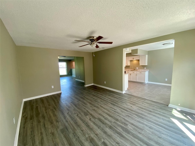 8922 Glacier Ave, Texas City, TX 77591 - unfurnished living room with dark wood-type flooring, baseboards, a textured ceiling, a sink, and a ceiling fan
