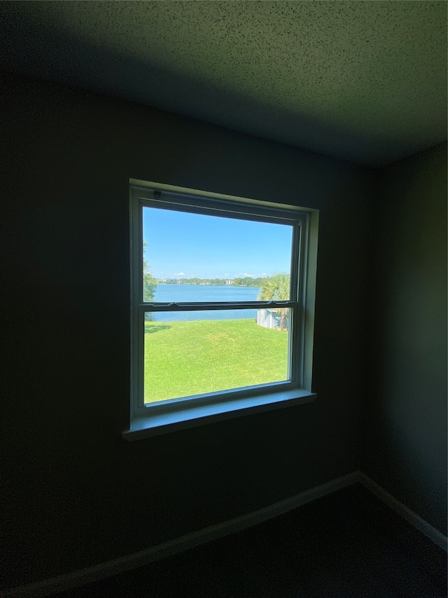 unfurnished room featuring a textured ceiling and a water view