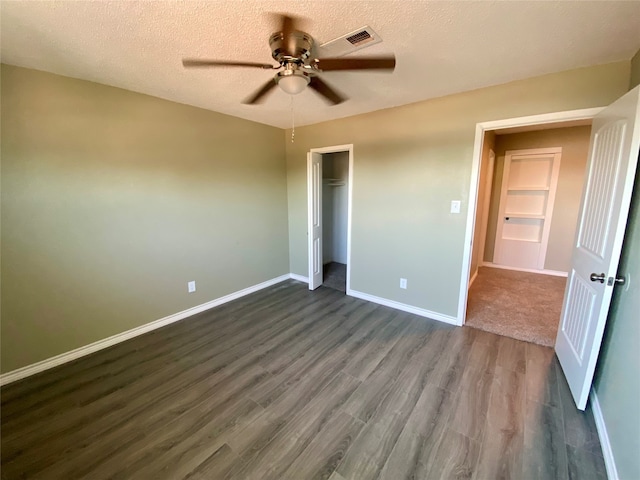 unfurnished bedroom featuring a closet, ceiling fan, a textured ceiling, and dark hardwood / wood-style flooring