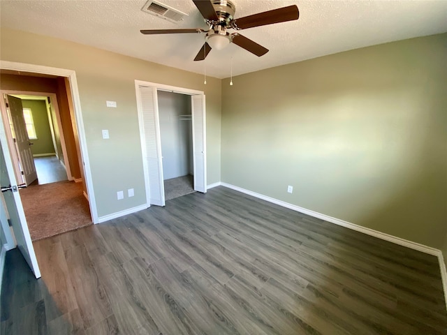 unfurnished bedroom featuring a textured ceiling, dark hardwood / wood-style flooring, ceiling fan, and a closet