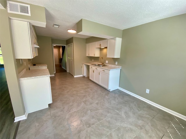 kitchen featuring a textured ceiling, sink, white dishwasher, and white cabinetry