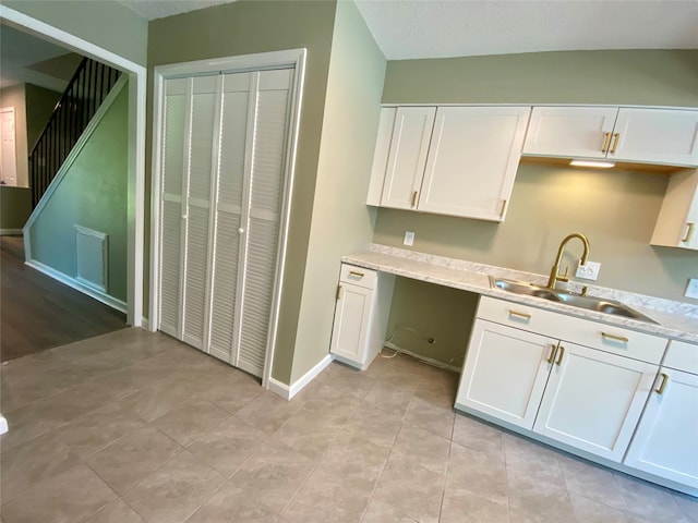 kitchen with white cabinets, light tile patterned floors, and sink