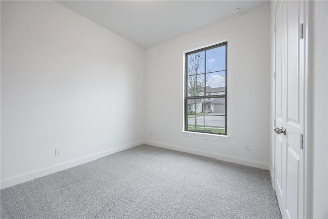 carpeted empty room featuring baseboards