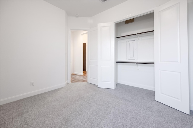 unfurnished bedroom with light colored carpet, baseboards, and a closet