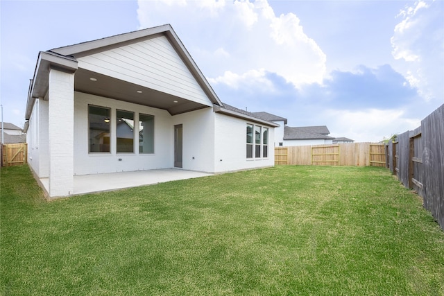 rear view of house with a yard, a fenced backyard, brick siding, and a patio