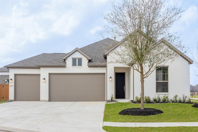 view of front facade with a front yard, concrete driveway, a garage, and a shingled roof