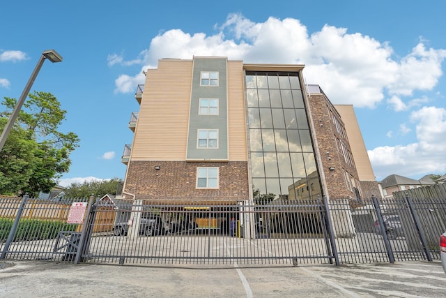 view of building exterior with uncovered parking and fence