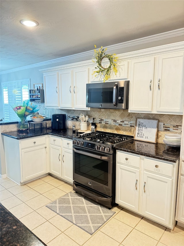 kitchen with ornamental molding, light tile patterned floors, stainless steel appliances, and white cabinets