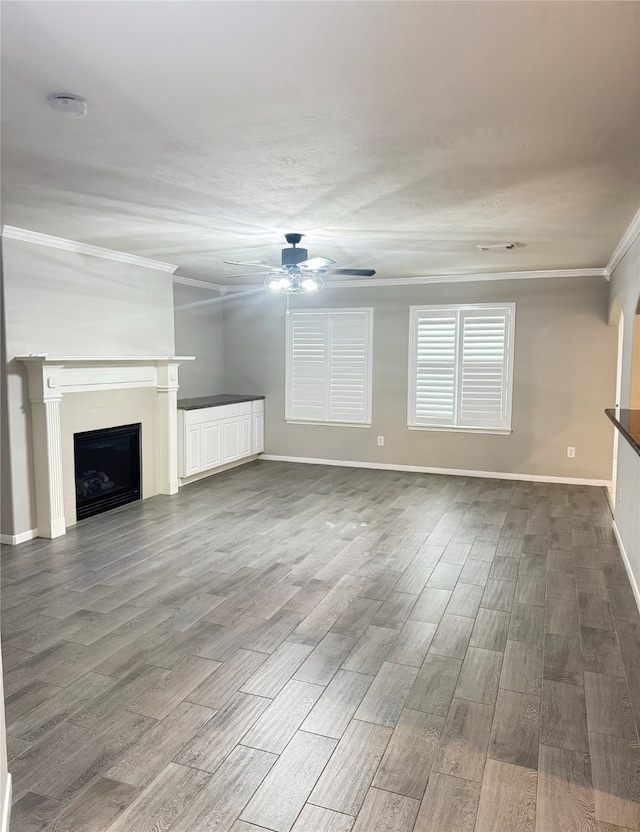 unfurnished living room with crown molding, hardwood / wood-style floors, and ceiling fan