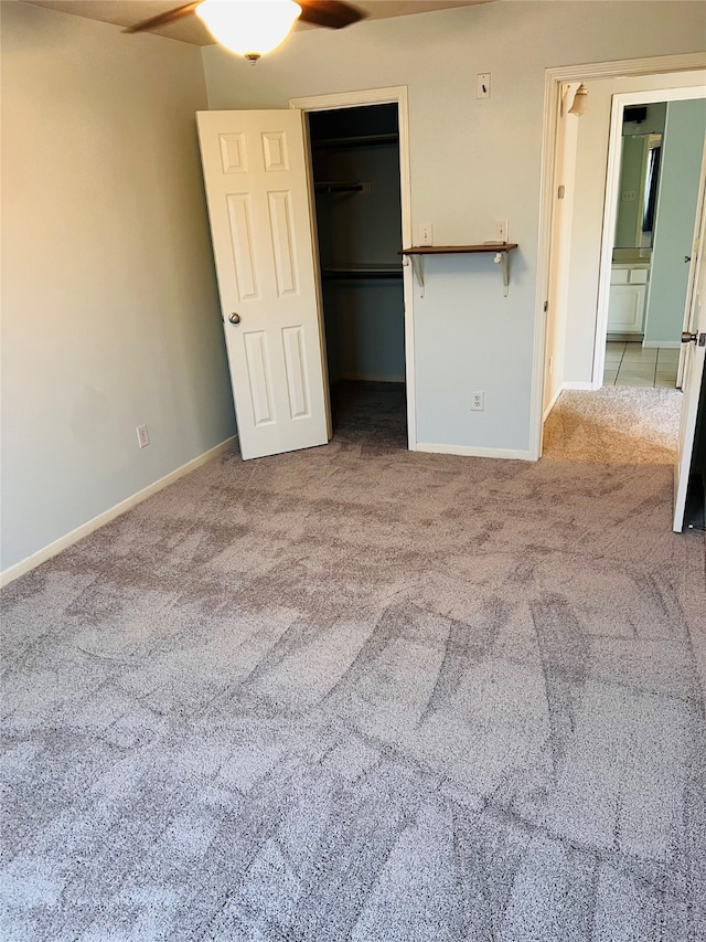 unfurnished bedroom with light carpet, ceiling fan, a closet, and a walk in closet