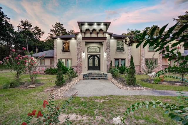 exterior entry at dusk with a lawn and french doors