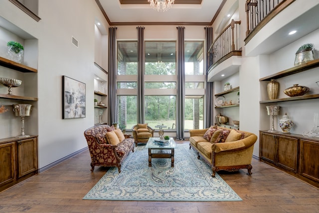 interior space with ornamental molding, a towering ceiling, dark hardwood / wood-style flooring, and a chandelier