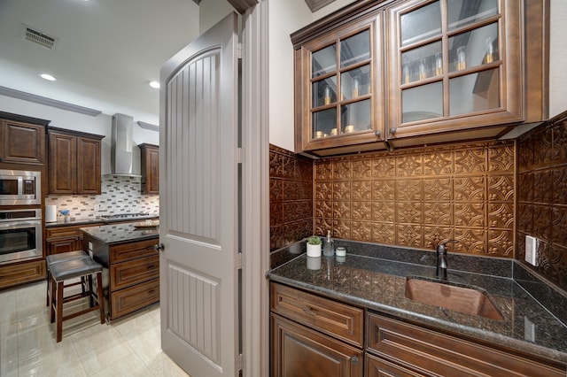 kitchen with dark stone counters, light tile patterned flooring, sink, wall chimney range hood, and appliances with stainless steel finishes