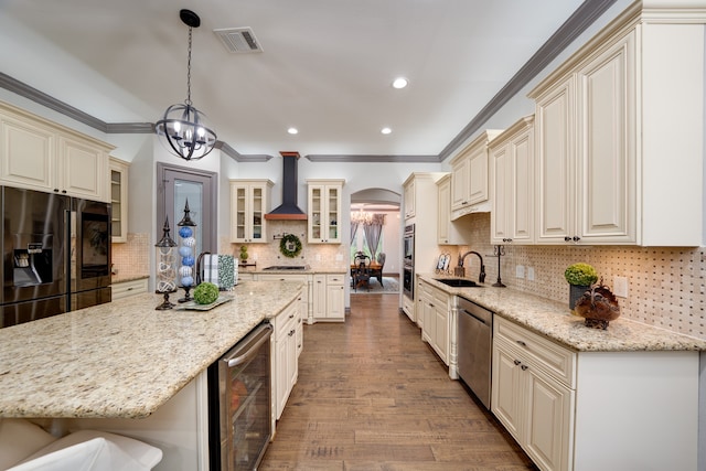 kitchen with hanging light fixtures, light hardwood / wood-style floors, wine cooler, wall chimney exhaust hood, and stainless steel appliances