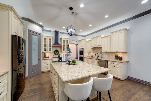 kitchen featuring pendant lighting, dark hardwood / wood-style floors, wall chimney range hood, and stainless steel appliances