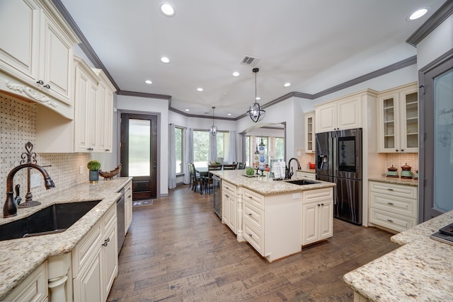 kitchen with an island with sink, hanging light fixtures, and light stone countertops