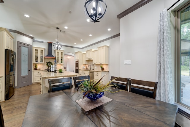 dining room with crown molding, sink, a chandelier, and light hardwood / wood-style flooring