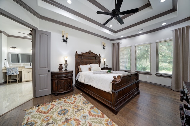 bedroom with dark hardwood / wood-style flooring, connected bathroom, a raised ceiling, crown molding, and ceiling fan